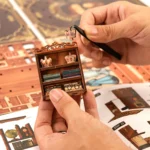Royal Tailor Shop Book Nook DIY assembly showing handmade installation of miniature crowns, wooden shelves and tiny decorative accessories.