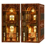 Dual view of the Philosophical Classics Library book nook, showing an illuminated front display and an angled side view with chandeliers, classical busts, display cases, bookshelves and carved wooden details.