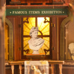 Close-up of the Philosophical Classics Library book nook, featuring a classical bust displayed beneath warm lighting inside an ornate museum-style exhibition area.