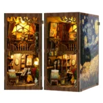 Dual view of the World in a Frame book nook, showing an illuminated front display and an angled side view with a two-level art studio, easels, paintings, brushes and a starry night panel.