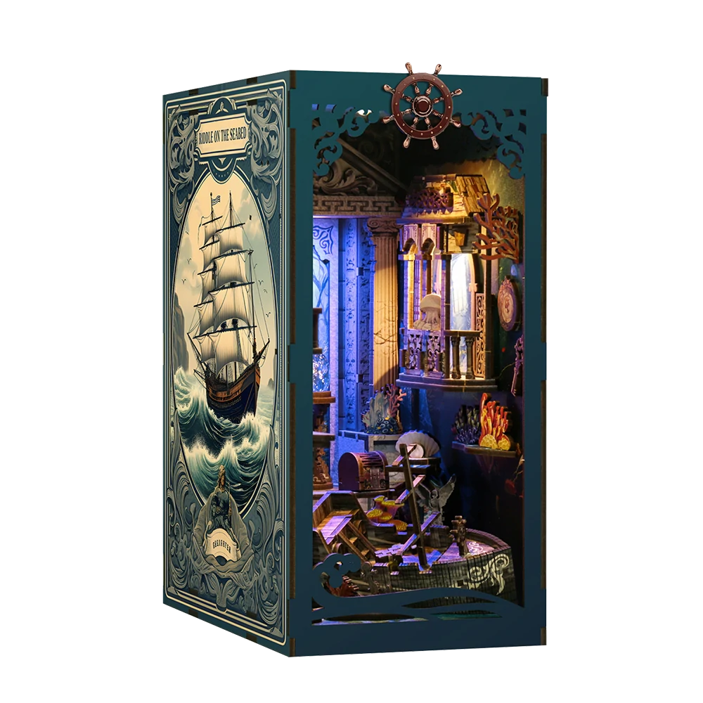 Illuminated angled view of the Underwater Enigma book nook, featuring a blue exterior panel, a sailing ship illustration, underwater ruins, coral decorations, a ship wheel and miniature furniture.