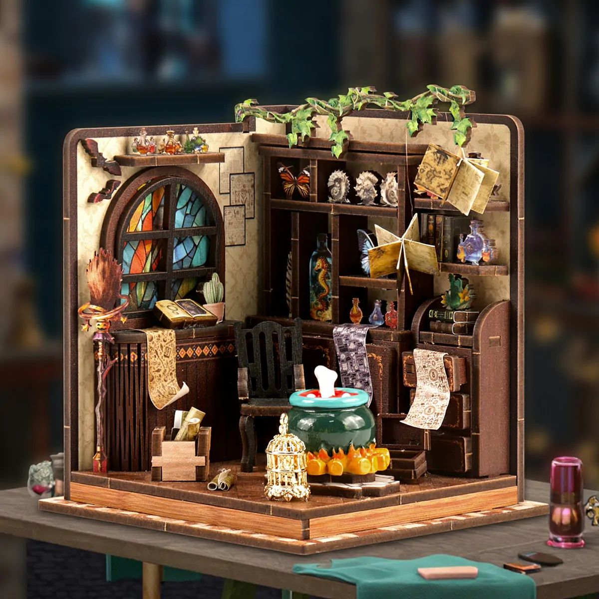 Completed Magic Potion Workshop DIY miniature model displayed on a worktable, featuring a bubbling cauldron, stained-glass window, potion bottles, magical books, butterflies, and alchemy decorations.