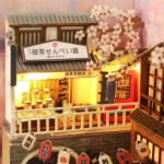 Illuminated detail of the Japan Street Cat DIY book nook featuring a miniature Japanese shop, display window, vending machine, and cherry blossoms.