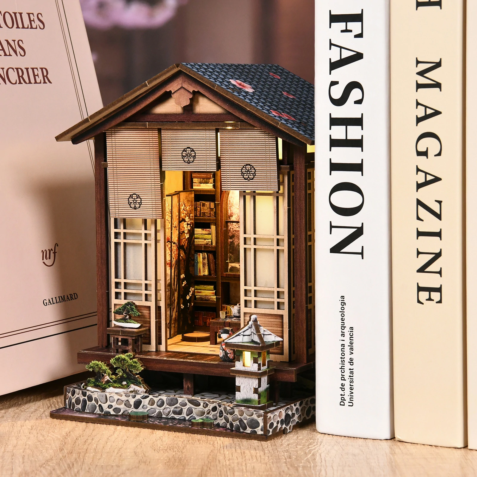 zen-mooslaterne-japanese-diy-book-nook-kit-between-books.jpg DIY Zen moss lantern book nook kit featuring an illuminated Japanese house, Zen garden, bonsai, stone lantern, and miniature interior details.