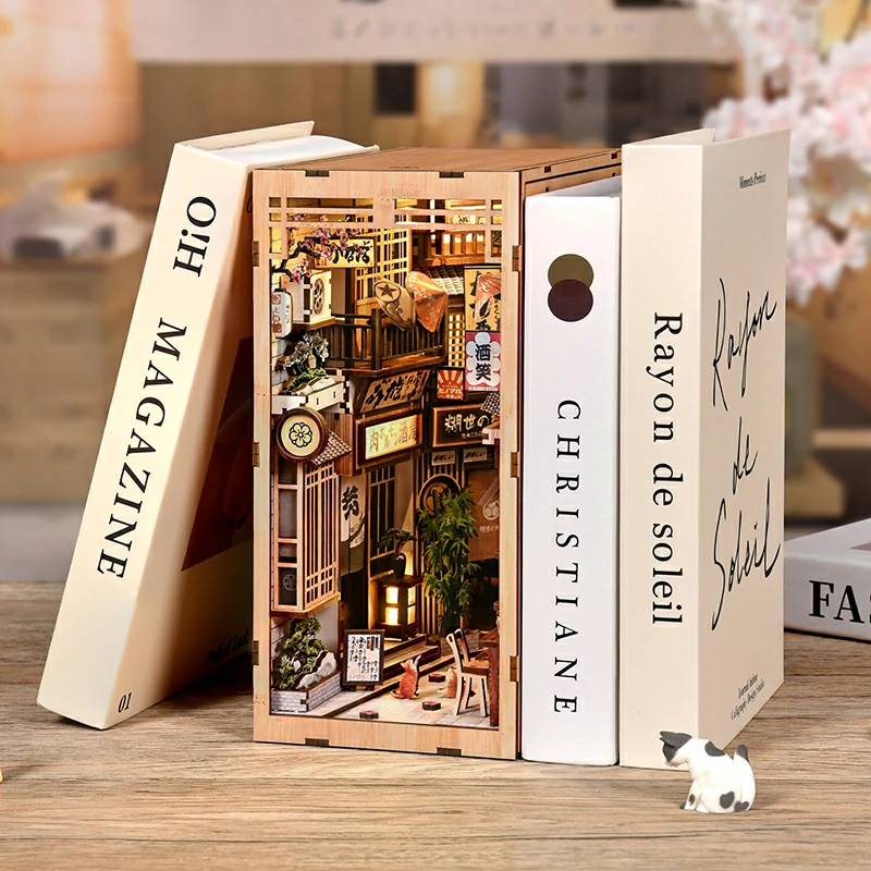 DIY Japanese Alley with Cat book nook kit, featuring an illuminated Japanese alleyway, miniature shops, lanterns, plants, and decorative cats.